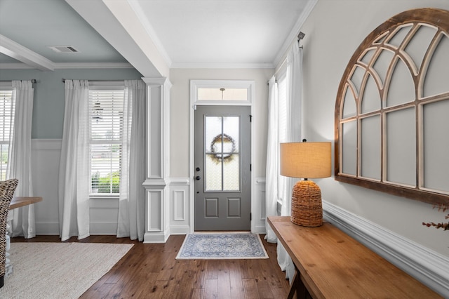 entrance foyer featuring dark wood-style flooring, healthy amount of natural light, ornamental molding, and wainscoting