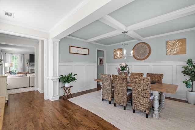 dining area featuring dark wood finished floors, a decorative wall, decorative columns, a chandelier, and beamed ceiling
