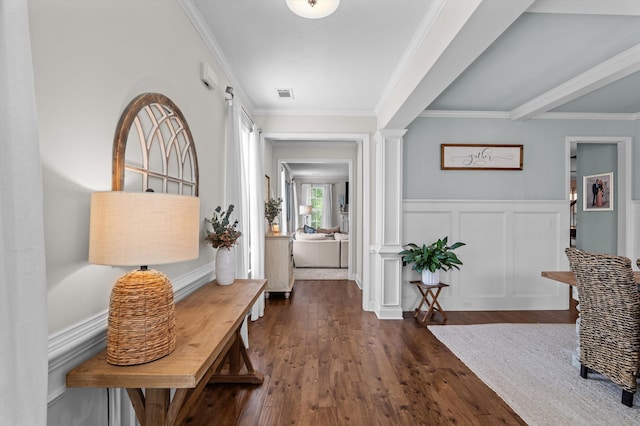 foyer with ornate columns, ornamental molding, dark wood-style flooring, a wainscoted wall, and a decorative wall