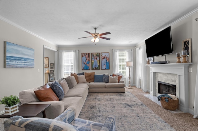 living area featuring ceiling fan, light carpet, a fireplace, crown molding, and baseboards