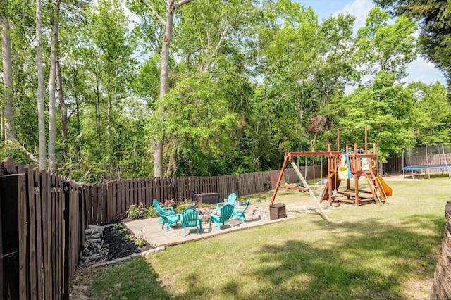 view of playground featuring a trampoline, an outdoor fire pit, a patio area, and view of scattered trees