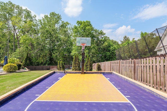 view of sport court featuring basketball hoop and view of scattered trees