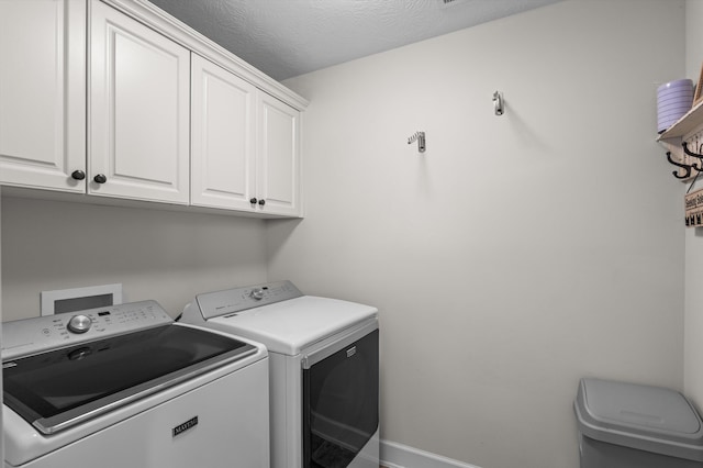 clothes washing area with cabinet space, washing machine and dryer, and baseboards