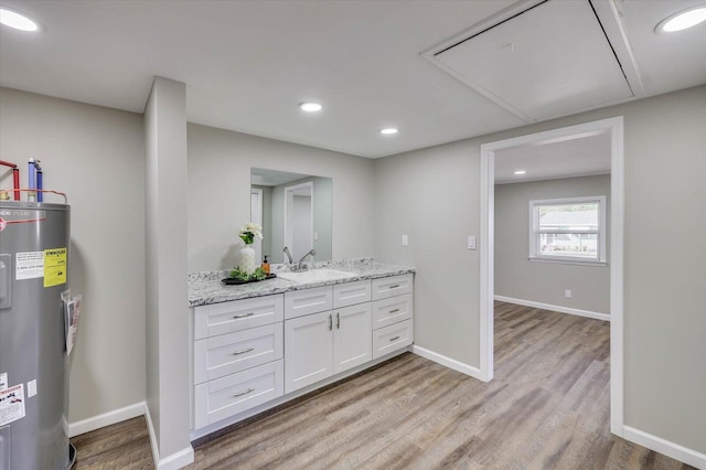 interior space featuring light stone countertops, light wood-type flooring, sink, water heater, and white cabinets