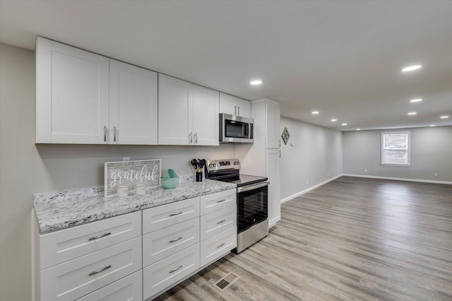 kitchen featuring white cabinets, light stone countertops, stainless steel appliances, and light hardwood / wood-style flooring