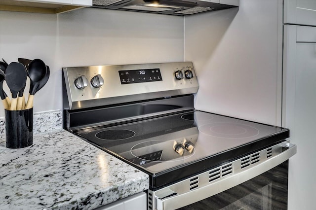 details with light stone countertops, stainless steel electric range oven, and exhaust hood