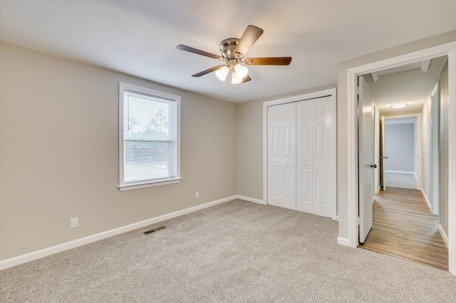 unfurnished bedroom featuring ceiling fan, a closet, and light colored carpet