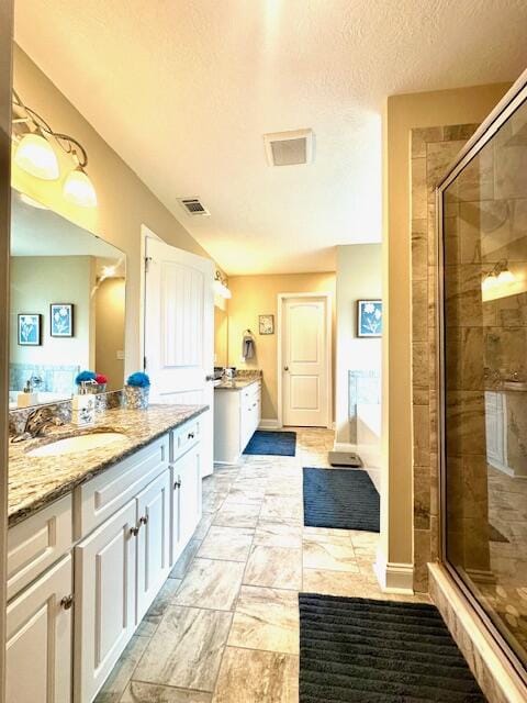 bathroom featuring vanity, a shower with shower door, and a textured ceiling