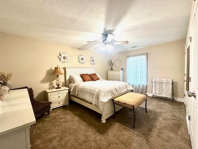 carpeted bedroom with ceiling fan and a textured ceiling