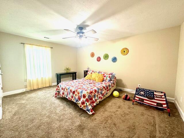 bedroom with ceiling fan, carpet, and a textured ceiling