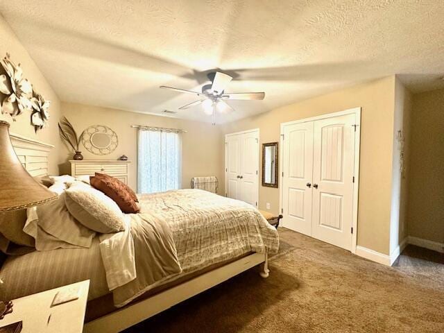 bedroom featuring two closets, ceiling fan, carpet, and a textured ceiling