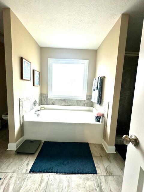 bathroom featuring a textured ceiling, toilet, and a bathtub