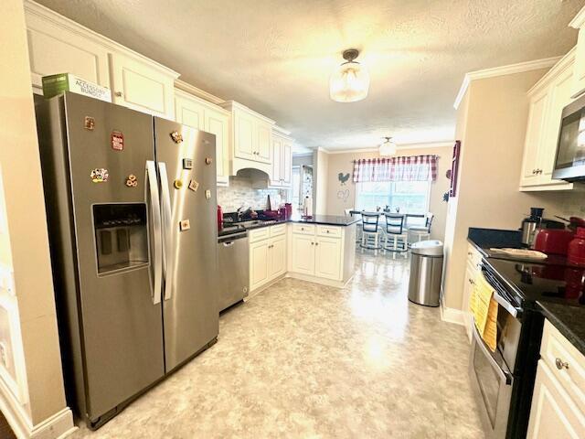 kitchen with kitchen peninsula, crown molding, white cabinetry, and stainless steel appliances