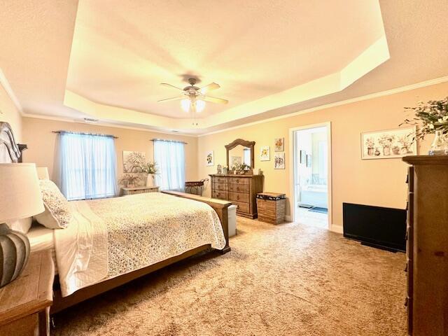 bedroom with carpet floors, a tray ceiling, ceiling fan, and ensuite bathroom