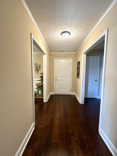 hall featuring dark hardwood / wood-style flooring, a textured ceiling, and ornamental molding