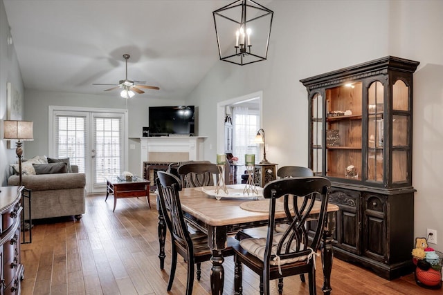 dining area with vaulted ceiling, wood-type flooring, plenty of natural light, and a tiled fireplace