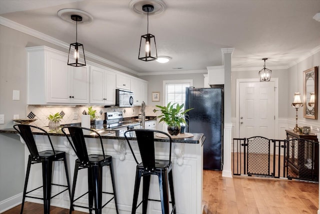 kitchen with electric range, light wood-style floors, freestanding refrigerator, white cabinetry, and a peninsula