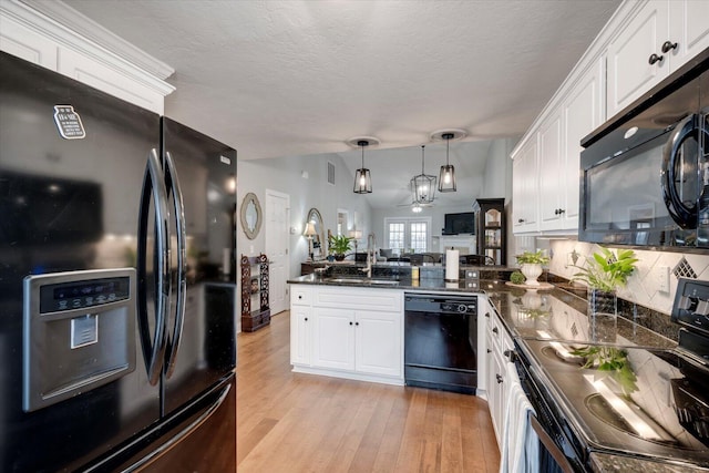 kitchen featuring white cabinets, light wood-style floors, lofted ceiling, black appliances, and a sink