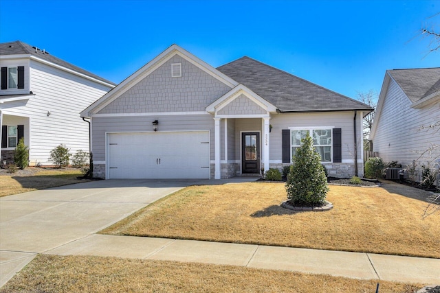 craftsman-style house featuring driveway, stone siding, a garage, and a front yard