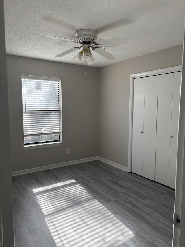 unfurnished bedroom with dark hardwood / wood-style flooring, ceiling fan, a closet, and a textured ceiling