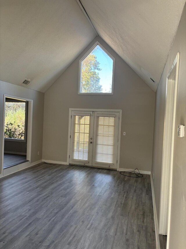 unfurnished living room with french doors, lofted ceiling, and dark wood-type flooring