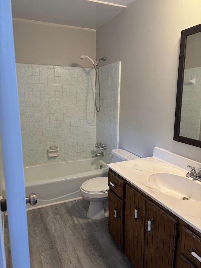 full bathroom with hardwood / wood-style flooring, tiled shower / bath combo, toilet, and vanity