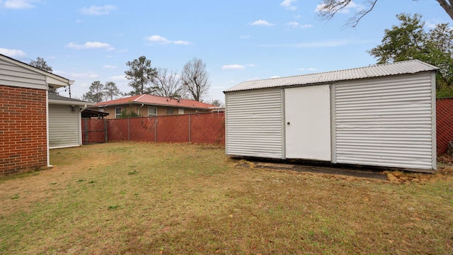 view of yard featuring a storage shed, a fenced backyard, and an outbuilding