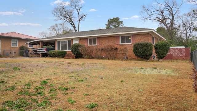 exterior space featuring brick siding, a front yard, fence, a carport, and driveway