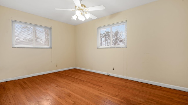 empty room featuring ceiling fan, plenty of natural light, baseboards, and wood finished floors