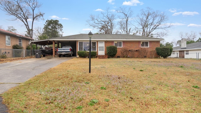 ranch-style home featuring brick siding, a front yard, crawl space, a carport, and driveway