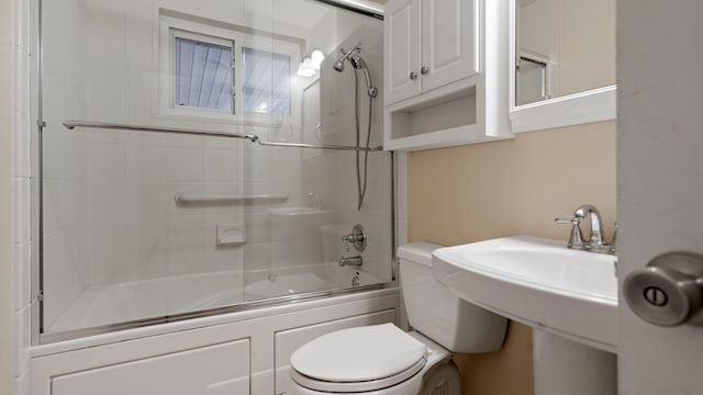 bathroom with toilet and bath / shower combo with glass door