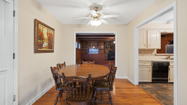 dining space with light wood-type flooring, a ceiling fan, and baseboards