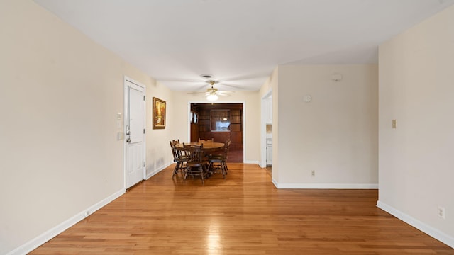 dining room featuring a ceiling fan, light wood-style flooring, and baseboards