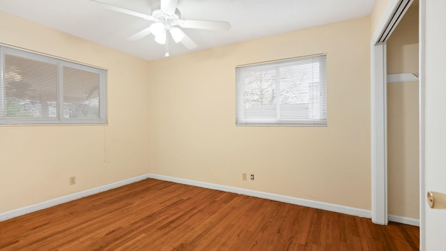 unfurnished bedroom featuring multiple windows, baseboards, and wood finished floors