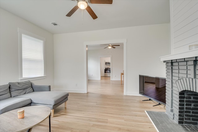 1107 Adrian St, Augusta, GA 30904 - living area featuring a ceiling fan, light wood finished floors, a brick fireplace, and baseboards
