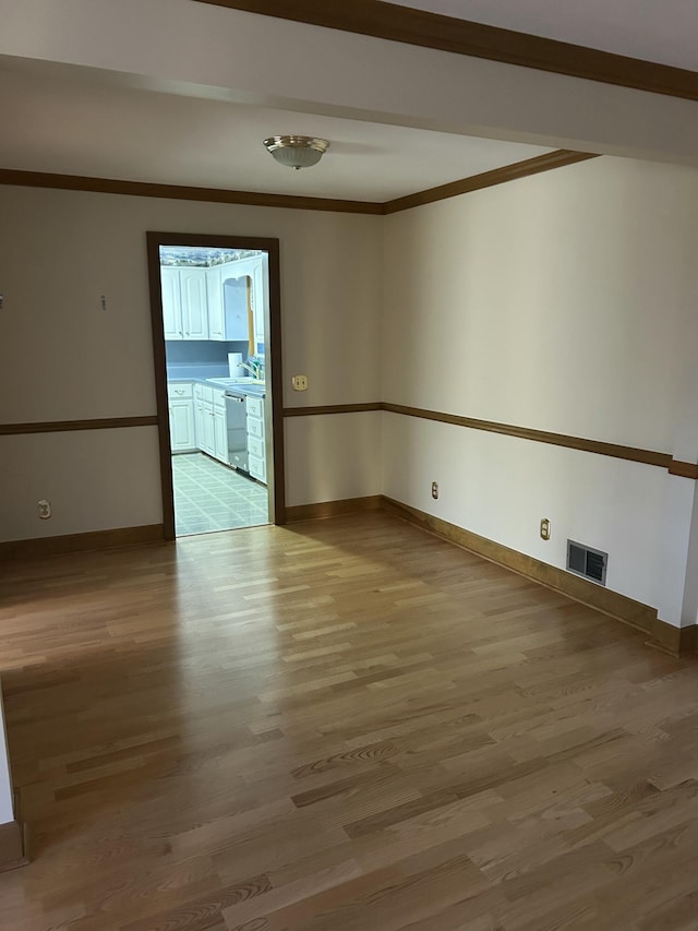 spare room featuring crown molding and light hardwood / wood-style flooring