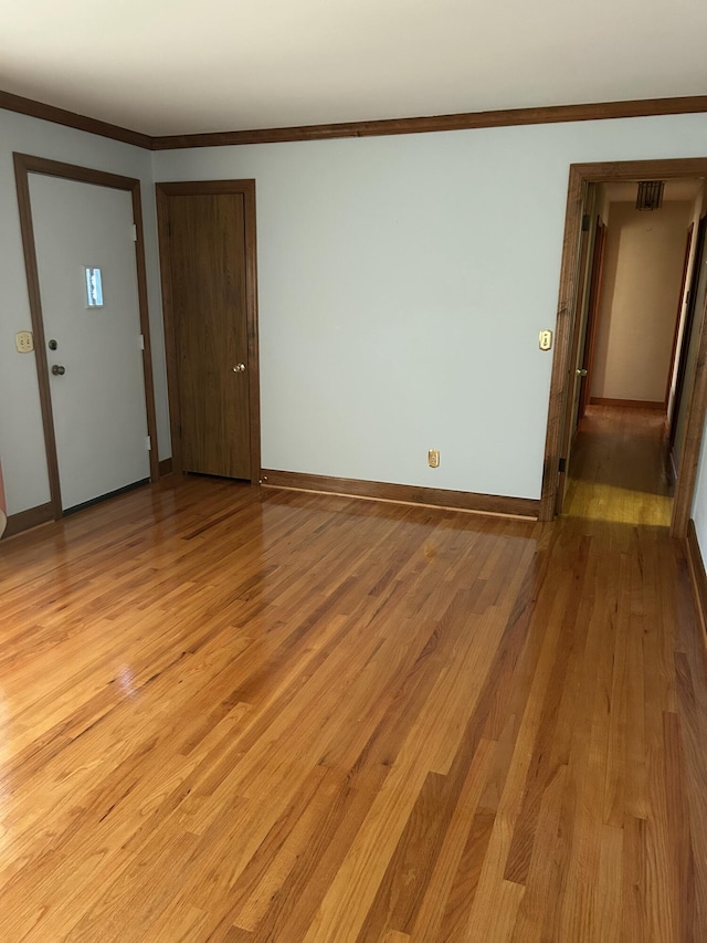 unfurnished room with ornamental molding and light wood-type flooring