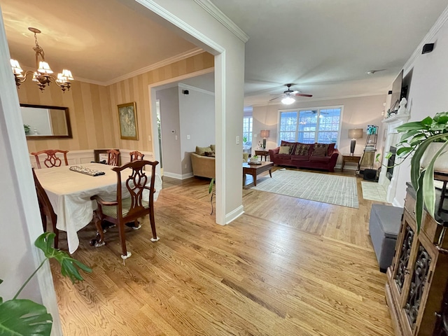 dining space with light hardwood / wood-style floors, ceiling fan with notable chandelier, and ornamental molding