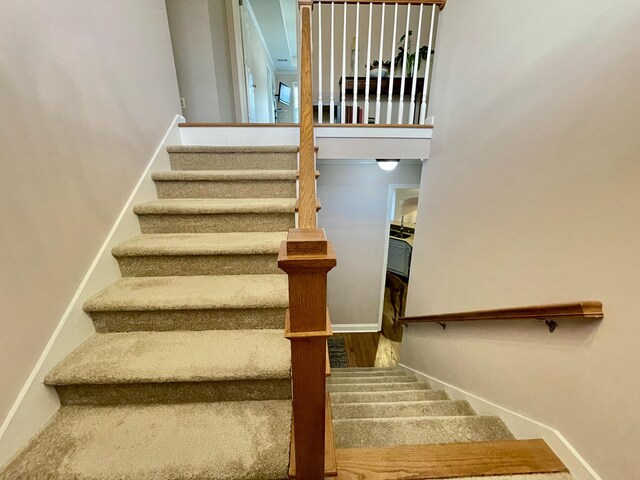 staircase with hardwood / wood-style floors and a towering ceiling