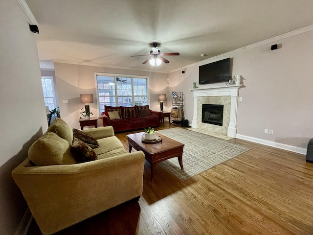 living room featuring a tile fireplace, ceiling fan, hardwood / wood-style floors, and ornamental molding