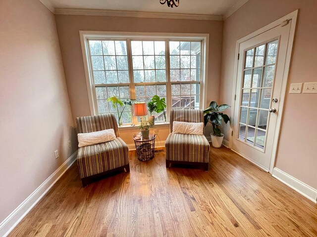 living area with light hardwood / wood-style floors and crown molding