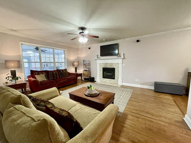 living room featuring hardwood / wood-style floors, ceiling fan, ornamental molding, and a fireplace