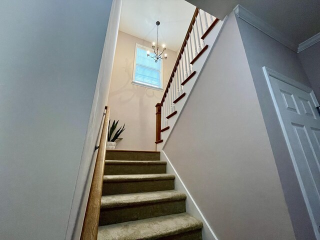 stairs with a notable chandelier and ornamental molding