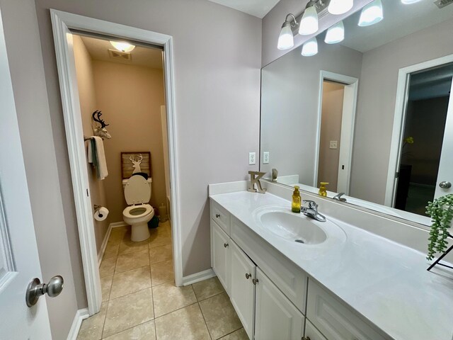 bathroom with toilet, vanity, and tile patterned floors