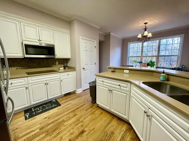 kitchen featuring decorative backsplash, appliances with stainless steel finishes, pendant lighting, a notable chandelier, and white cabinets