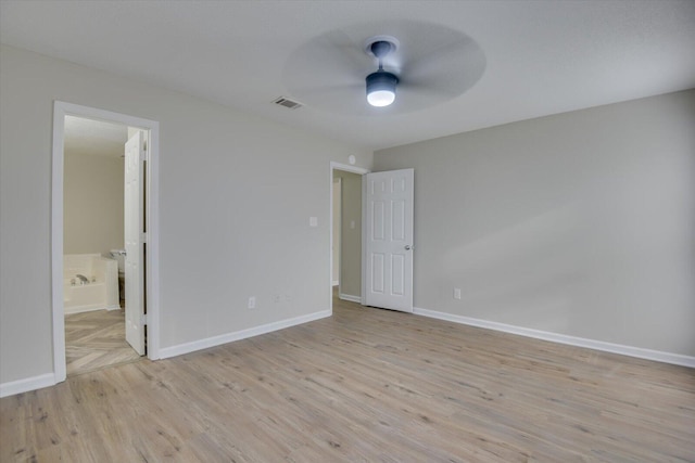 unfurnished bedroom with light wood-style flooring, ensuite bath, a ceiling fan, visible vents, and baseboards