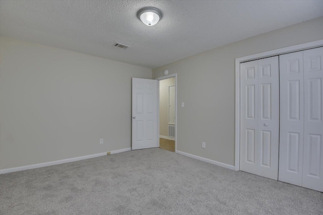 unfurnished bedroom featuring visible vents, baseboards, a closet, a textured ceiling, and carpet flooring
