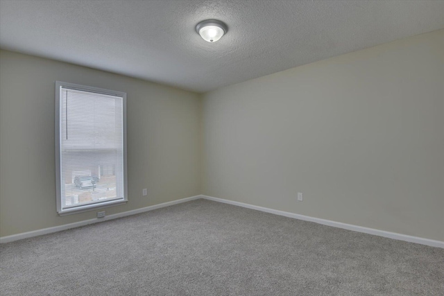 carpeted empty room featuring a textured ceiling and baseboards