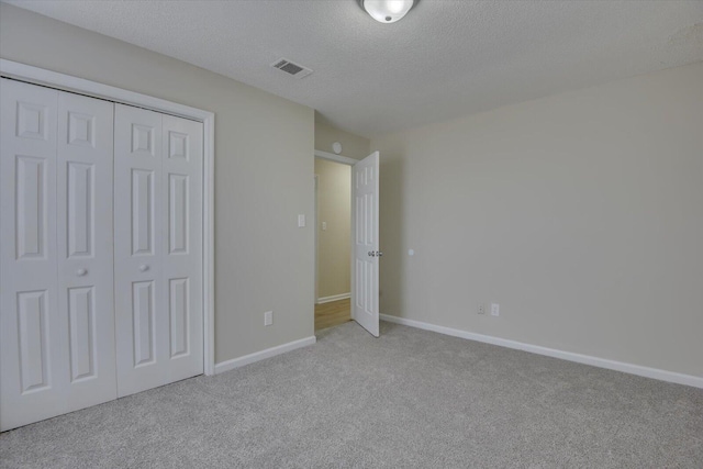 unfurnished bedroom with visible vents, baseboards, a closet, carpet, and a textured ceiling