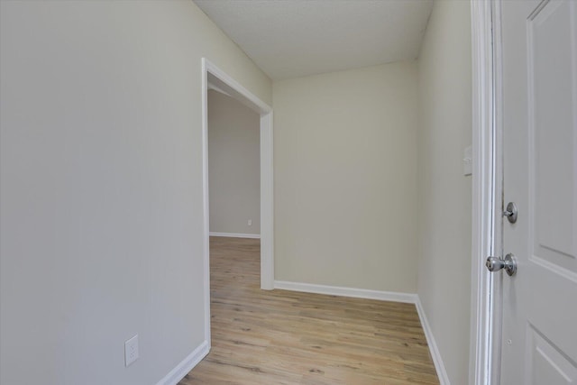 hallway featuring light wood-style floors and baseboards